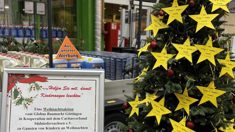 Das Foto zeigt einen mit gelben Sternen geschmückten Weihnachtsbaum neben einem Aufsteller, der die Aktion erklärt.