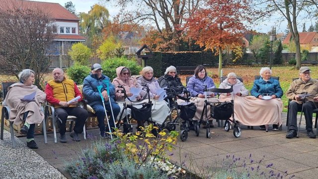 Das Foto zeigt Menschen, die in einer Reihe im Garten sitzen.