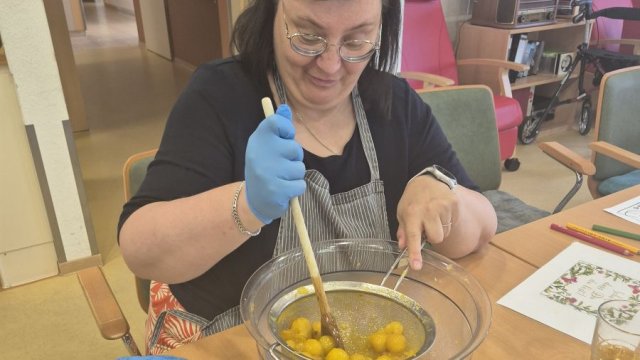 Das Foto zeigt Annett Reimann beim Verarbeiten der Mirabellen. Sie rührt die Früchte in einem Sieb. | Foto: Caritas
