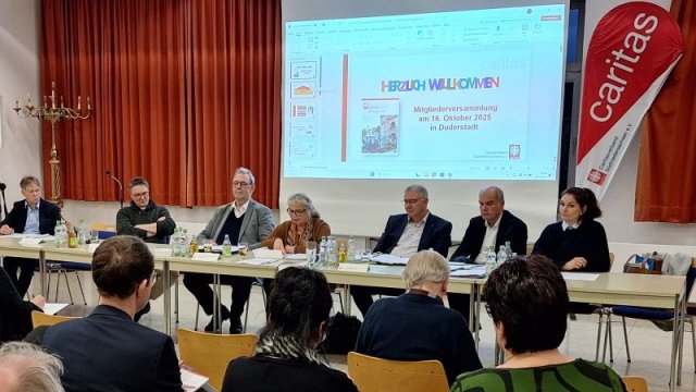 Das Bild zeigt Mitglieder des Caritasrats und des Vorstandsteams, wie sie gemeinsam der Mitgliederversammlung vorsitzen.